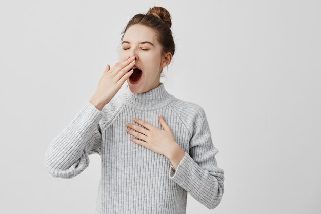 Tired woman yawning covering open mouth with hand need rest. Young female worker being sleepy head can't wake up having insomnia. Chain reaction