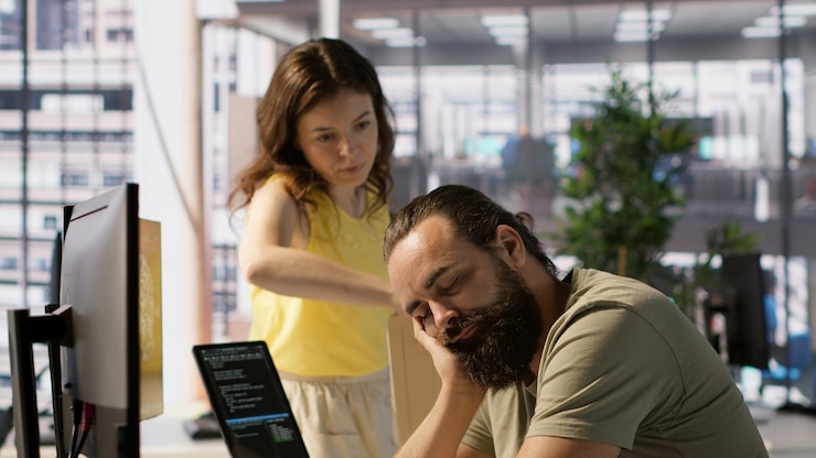 Free Photo tired worker caught asleep at desk in office by colleague laughing about it