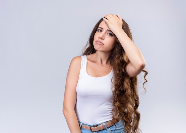 Tired young beautiful girl putting hand on head on isolated white wall with copy space