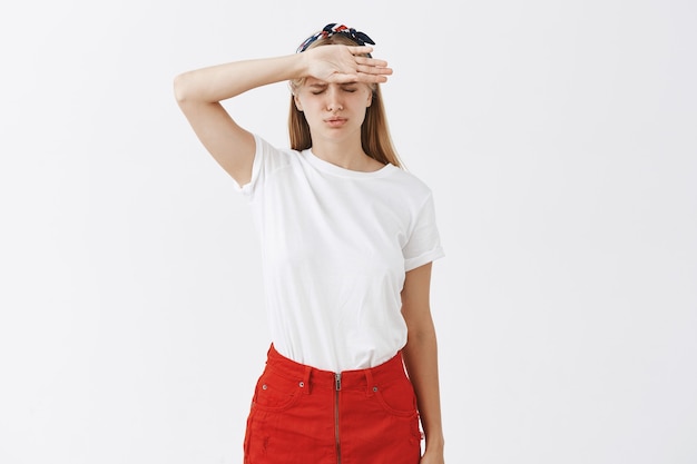 Free photo tired young blond girl posing against the white wall