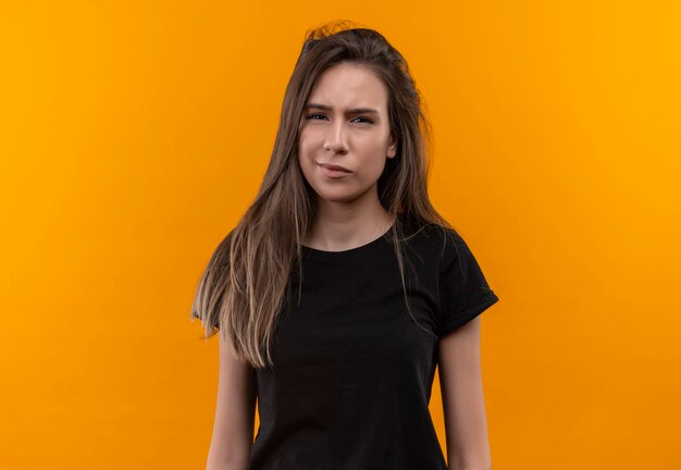 Tired young caucasian girl wearing black t-shirt on isolated orange wall