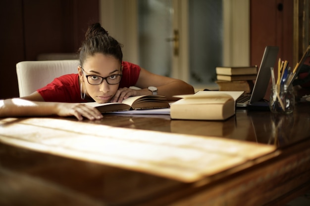 Tired young female doing homework at home