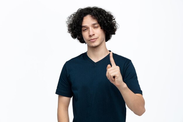 Tired young handsome man looking at camera showing one with hand isolated on white background