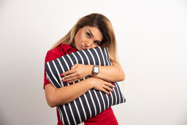 Tired young woman hugging her pillow on whiten background.