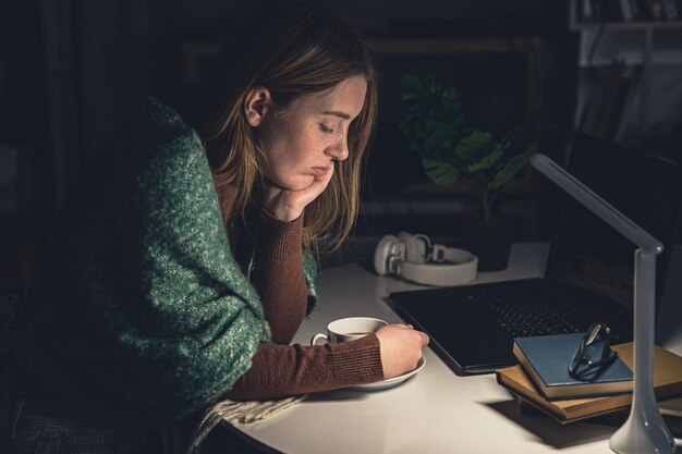 Free photo tired young woman at the workplace wants to sleep late at night