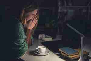 Free photo tired young woman at the workplace wants to sleep late at night