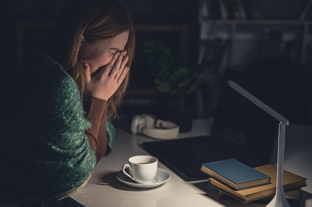 tired young woman at the workplace wants to sleep late at night