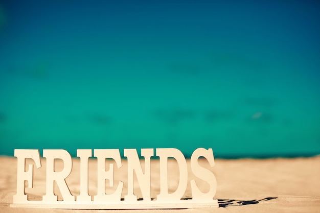 Title friends on white sand behind blue sky near ocean