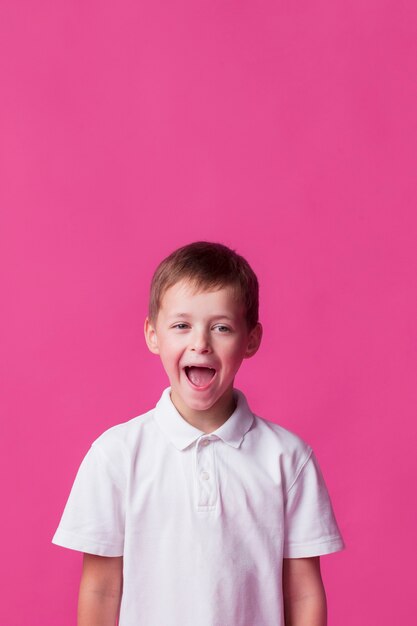tittle boy standing near pink wall with mouth open
