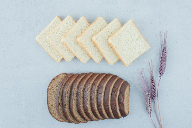 Toast and black bread slices on stone surface with wheat