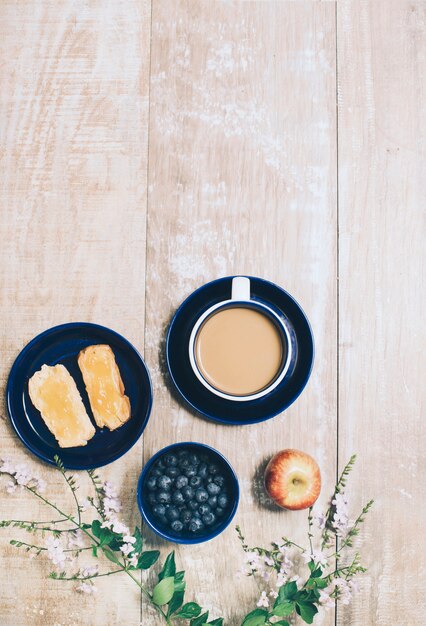 Toast bread; blueberries; apple and cup of coffee on wooden textured backdrop