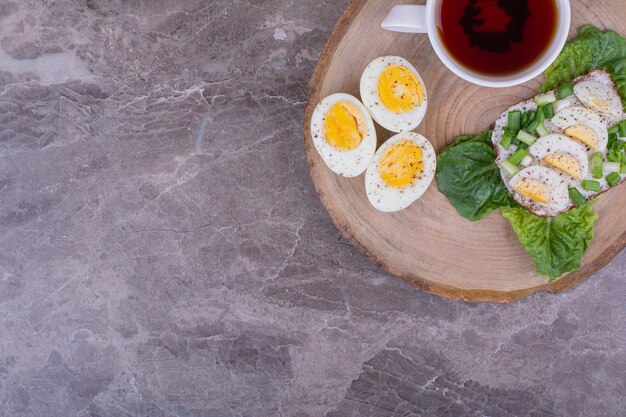 Toast bread with boiled eggs and herbs served with a cup of tea.