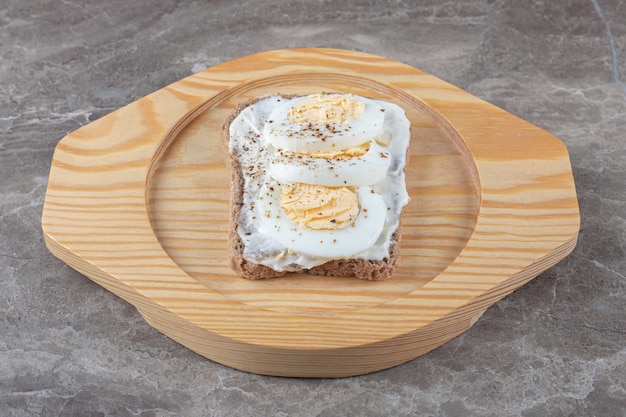 Toast bread with boiled eggs on wooden plate. 