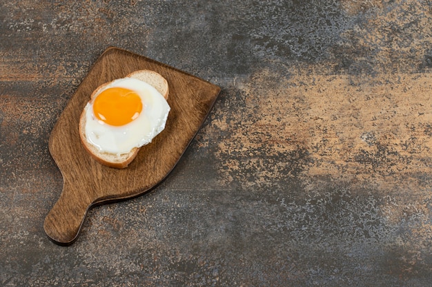 Toast bread with egg on wooden board.