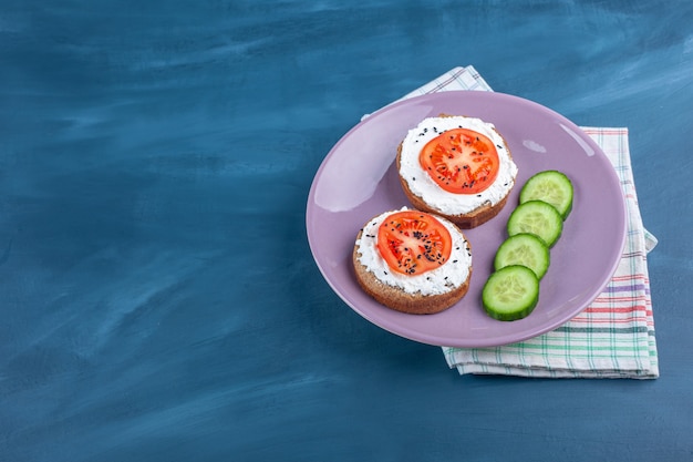 Toast bread with sour cream and sliced vegetables on purple plate. 