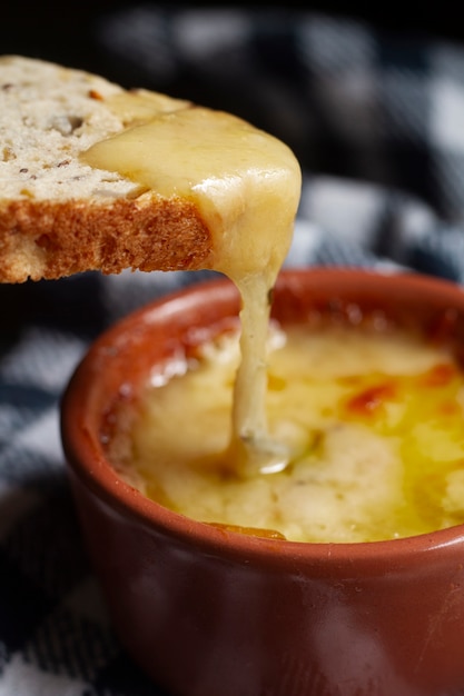 Бесплатное фото Тост, смоченный в миске с расплавленным сыром