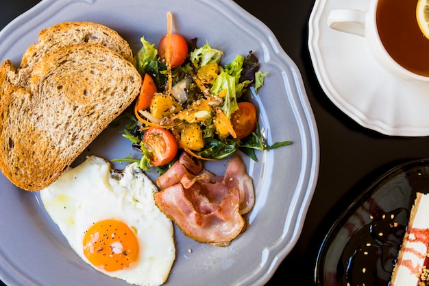 Toast; salad; fried eggs; bacon on ray plate