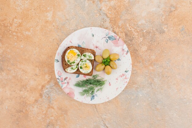 Toast with boiled eggs, olive on white plate