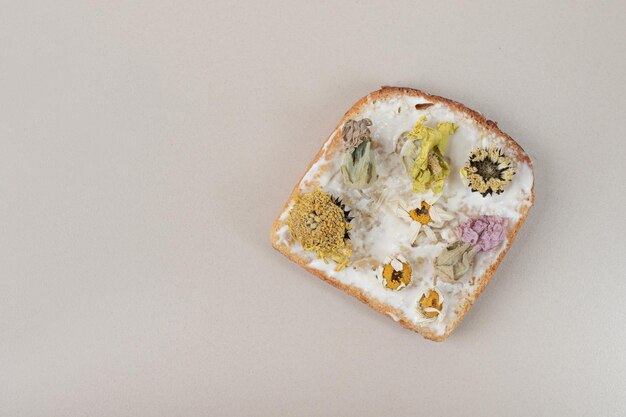 Toast with dried flowers and flour on gray table .