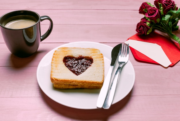 Toast with jam in heart shape with roses and coffee 