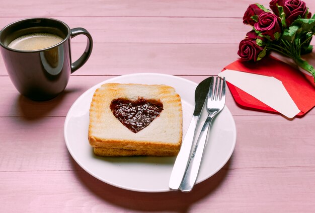 Toast with jam in heart shape with roses and coffee 