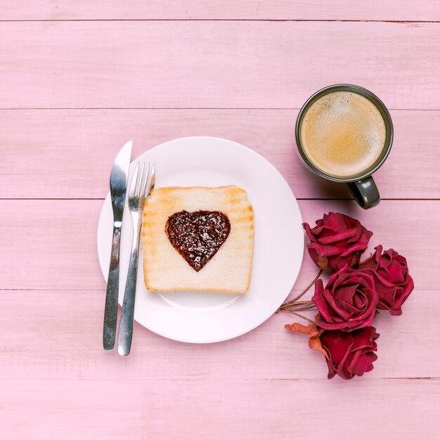 Toast with jam in heart shape with roses and coffee 