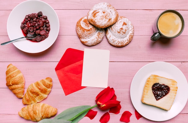 Бесплатное фото Тост с джемом в форме сердца с тюльпаном, ягодами и чистым листом бумаги