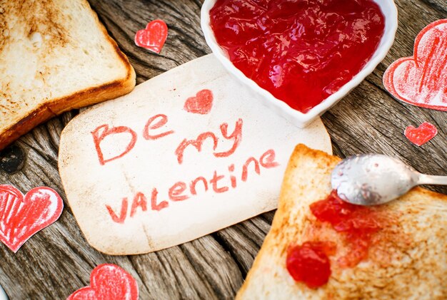 Toast with strawberry jam Be My Valentine white message card with hand made hearts Valentine's Day