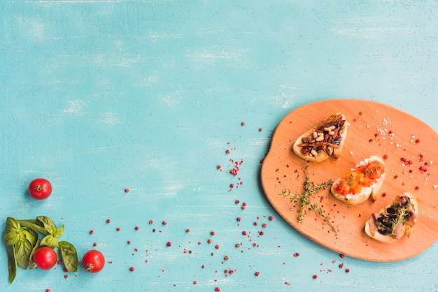 Toasted healthy sandwiches with basil; tomatoes and red peppercorn on colored background