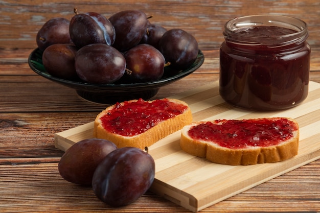 Toastes with plum confiture in a glass jar.