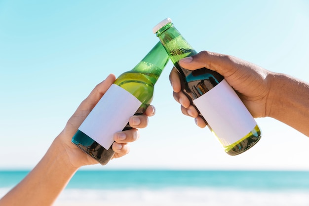 Toasting with two bottles near sea