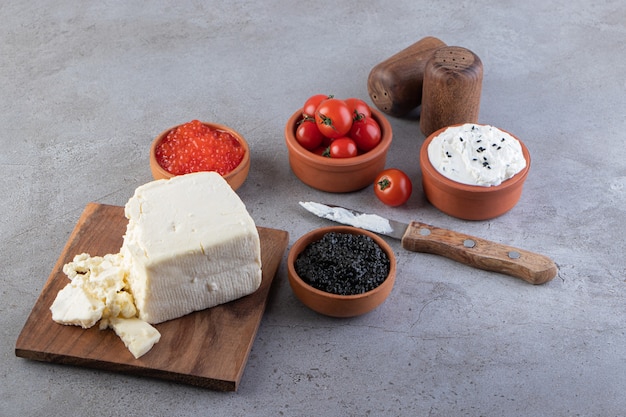 Toast con burro e pomodorini rossi adagiati su una superficie di marmo.