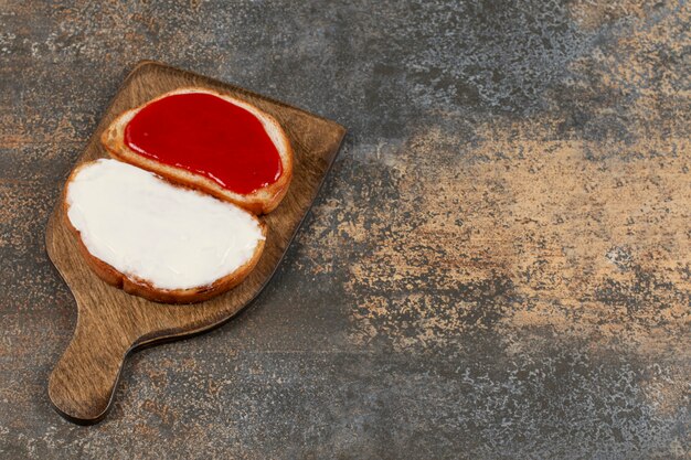 Free photo toasts with jam and sour cream on wooden board.