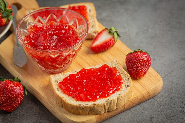 Toasts with strawberry jam on old dark background