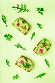 Toasts with watemelon radish avocado and flex seeds on color background top view flat lay