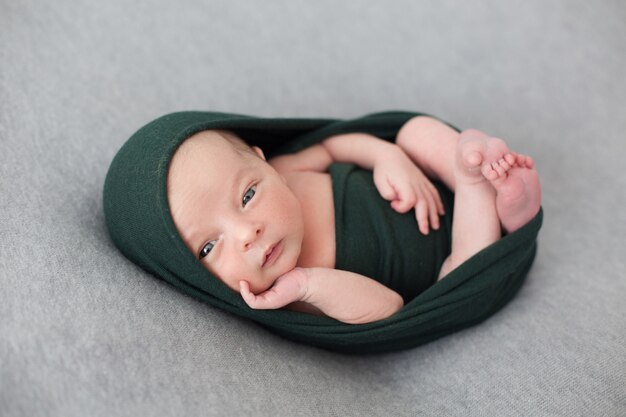 A toddler baby wrapped with black streth tissue.