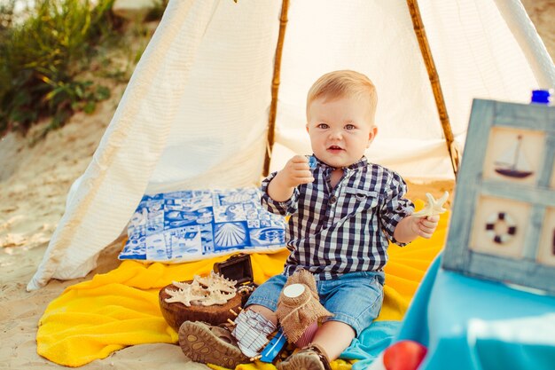 «Мальчик-малыш, сидящий на одеяле под шатер»