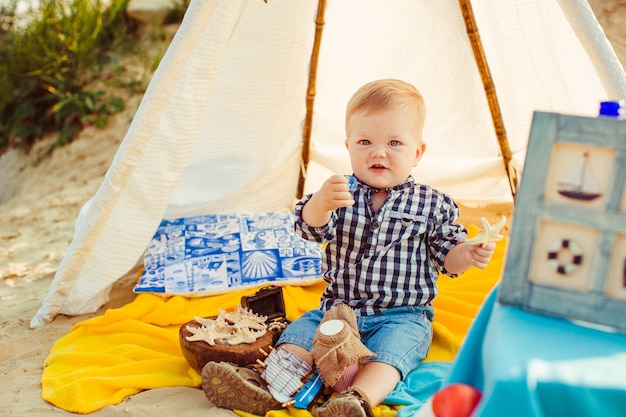 "Toddler boy sitting on blanket under tent"