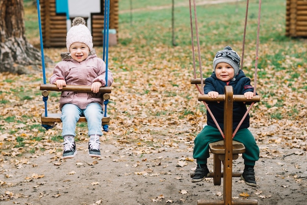 Toddler children swinging in park