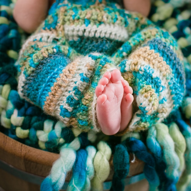 "Toddler lying on colorful knitted fabric"