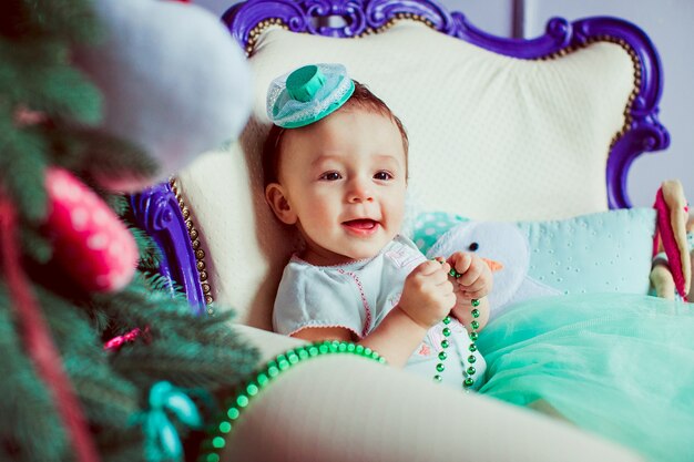 "Toddler playing with garland sitting in chair"