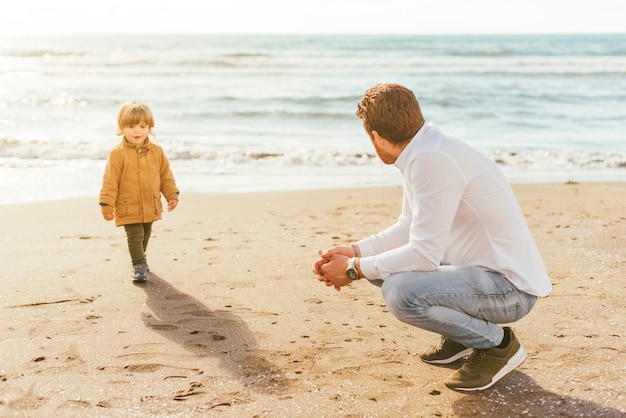 Toddler walking on beach with dad