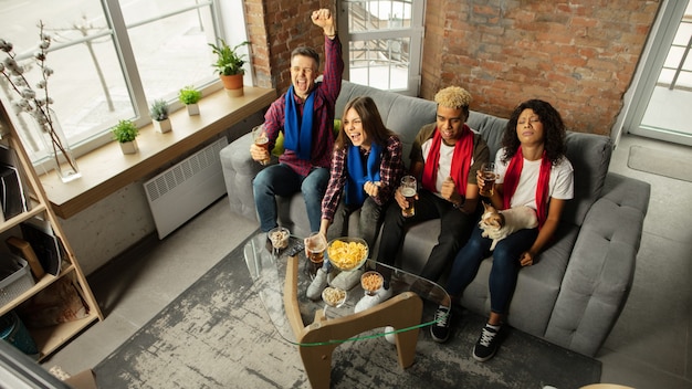 Togetherness. Excited people watching sport match, championship at home. Multiethnic group of friend, fans cheering for favorite national basketball, tennis, soccer, hockey team. Concept of emotions.