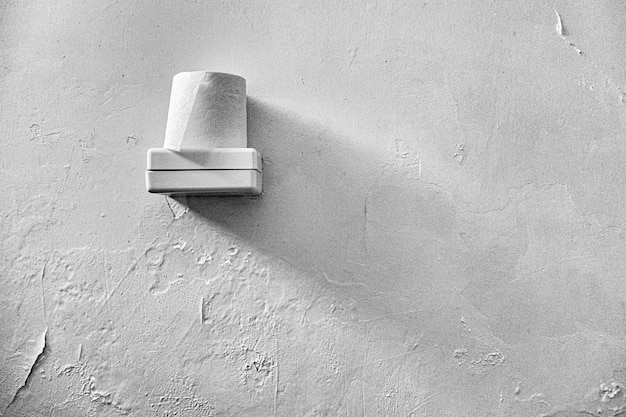 Toilet paper placed on top of a white plastic box with a white wall in the background