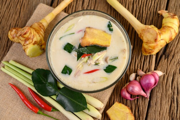 Tom Kha Kai in a bowl with kaffir lime leaves, lemongrass, red onion, galangal and chilli.