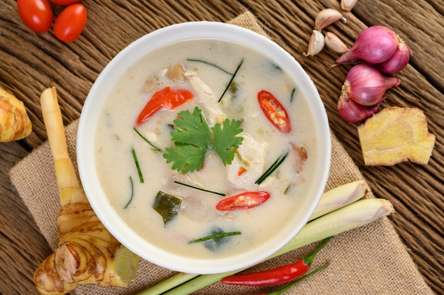 Tom Kha Kai in a bowl with kaffir lime leaves, lemongrass, red onion, galangal and chilli.