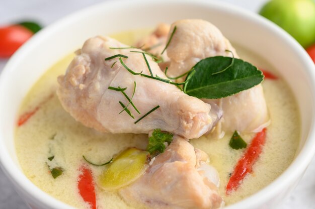 Tom Kha Kai in a bowl with kaffir lime leaves, lemongrass, red onion, galangal and chilli.