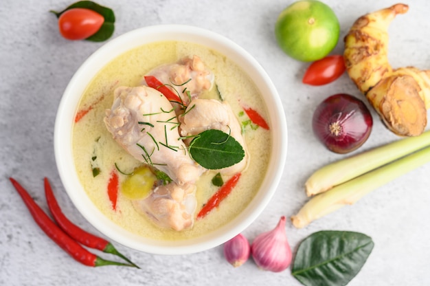 Tom Kha Kai in a bowl with kaffir lime leaves, lemongrass, red onion, galangal and chilli.