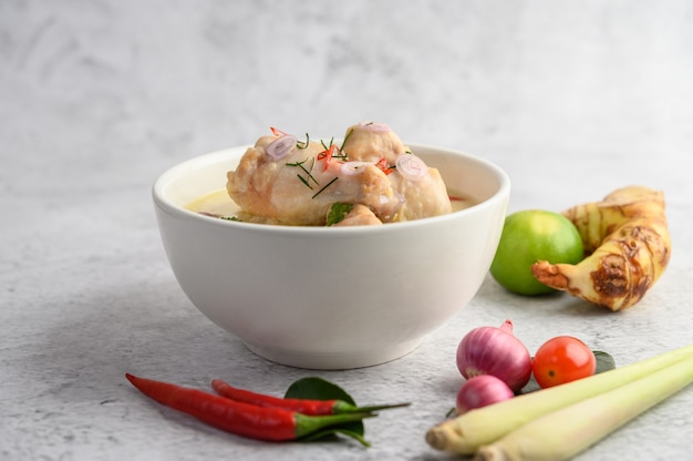 Tom Kha Kai in a bowl with kaffir lime leaves, lemongrass, red onion, galangal and chilli.