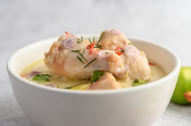 Tom Kha Kai in a bowl with kaffir lime leaves, lemongrass, red onion, galangal and chilli.